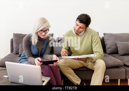 Geschäftsmann schreibt, während Kollege während eines Meetings im Büro einen Laptop benutzt Stockfoto