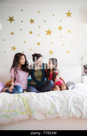 Glückliche Familie genießen, während auf dem Bett zu Hause sitzen Stockfoto