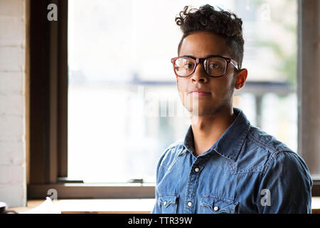 Portrait des jungen Mannes gegen Glasfenster im Cafe sitzen Stockfoto