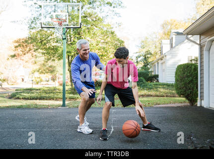 Großvater spielen Basketball mit Enkel im Hinterhof Stockfoto