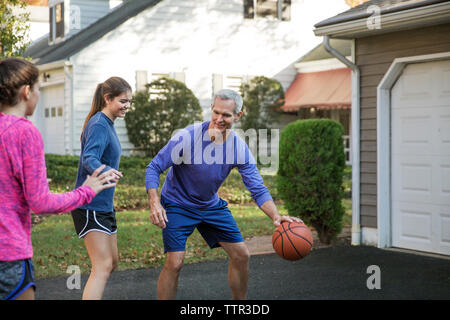 Großvater spielen Basketball mit enkelinnen im Hinterhof Stockfoto