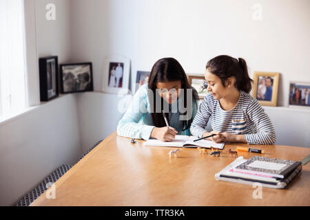 Schwestern studieren an der Tabelle durch Fenster Stockfoto