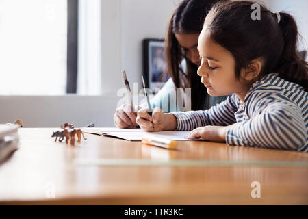 Mädchen studieren während am Tisch sitzen Stockfoto