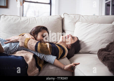 Fröhliche Mutter und Tochter auf dem Sofa zu Hause genießen. Stockfoto