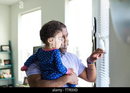 Vater und Tochter durch Jalousien zu Hause suchen Stockfoto