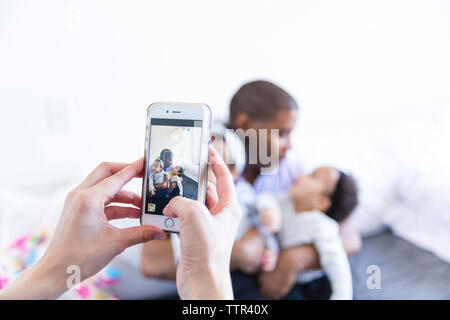 7/8 Hände von Frau fotografieren Mann mit Baby Girls zu Hause Stockfoto