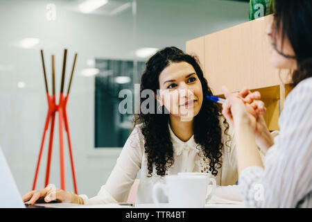 Weibliche Unternehmer diskutieren beim Sitzen am Schreibtisch im Büro Stockfoto