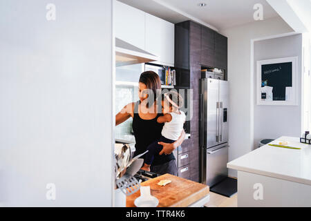 Mutter, die niedliche Tochter beim Stehen in der Küche zu Hause Stockfoto