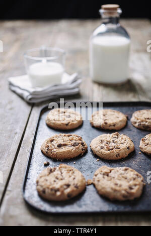 In der Nähe von Chocolate Chip Cookies auf Backblech mit Milch über Holz- Tabelle Stockfoto