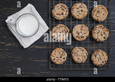 Ansicht von oben von Chocolate Chip Cookies auf dem Kochen Rack mit Milch über Holz- Tabelle Stockfoto