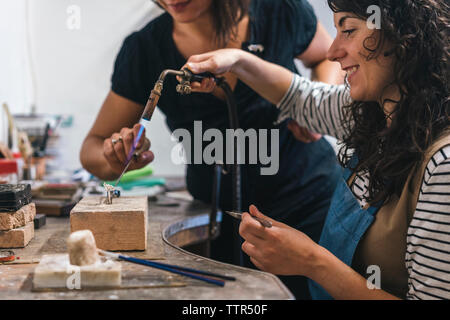 Mittelteil der Lehrer Unterstützung der Schüler bei der Ring am Tisch in der Werkstatt Stockfoto