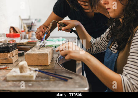 Mittelteil der Lehrer Unterstützung der weiblichen Teilnehmer über Brenner am Ring am Workshop Stockfoto