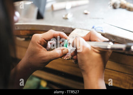 7/8 Hände weiblichen handwerkliche Gestaltung Ring mit Ausrüstung auf dem Tisch in der Werkstatt Stockfoto