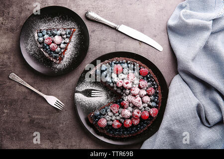 Köstliche Schokoladentorte mit Beeren in Scheiben geschnitten auf schwarze Platte Stockfoto