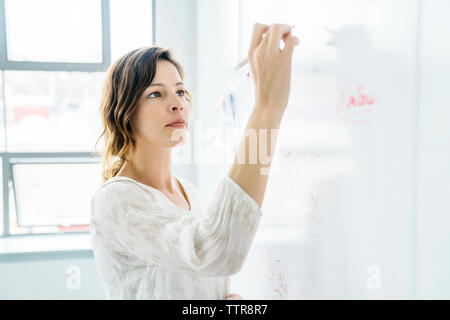 Seitenansicht des geschäftsfrau Schreiben auf dem Whiteboard Stockfoto