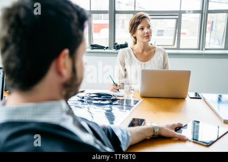 Geschäftsleute, die während des Meetings im Konferenzraum sitzen Stockfoto