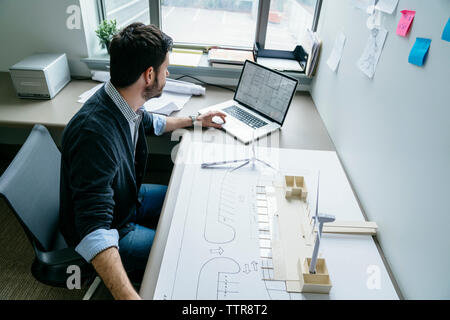 Hohe Betrachtungswinkel der Geschäftsmann mit Laptop beim Anordnen von wind turbine Modelle Stockfoto