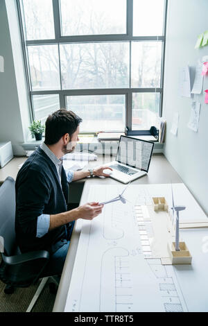 Hohe Betrachtungswinkel der Geschäftsmann mit Laptop halten wind turbine Modelle Stockfoto