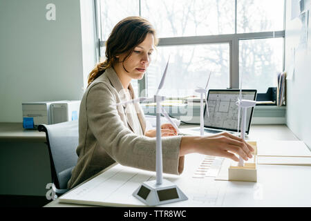 Seitenansicht der Geschäftsfrau, die die Windenergieanlage Modelle auf Schreibtisch Stockfoto