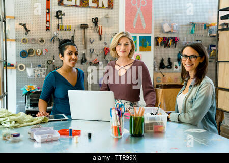 Portrait von zuversichtlich Geschäftsfrauen durch Werkbank stehend Stockfoto