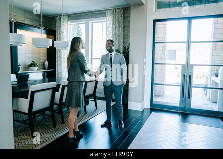 Volle Länge des Business Menschen die Hände schütteln, während in board Zimmer im Amt stehende Stockfoto