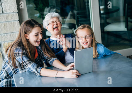 Hohe Betrachtungswinkel von Happy Enkelinnen und mit Tablet Computer Großmutter auf der Veranda Stockfoto