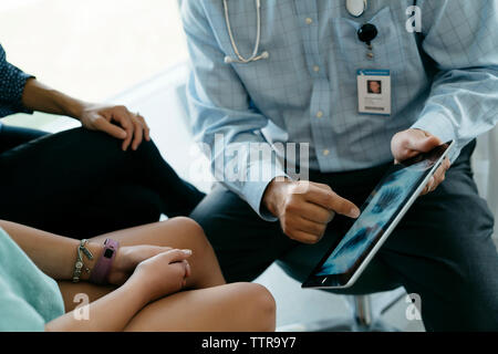 Mittelteil der Kinderarzt zeigt x-ray Image auf Tablet Computer zu Mutter und Tochter im Untersuchungsraum Stockfoto