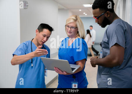 Arzt diskutieren über Laptop mit Kollegen beim Stehen in Krankenhaus Flur Stockfoto