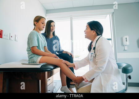 Mutter an der Kinderarzt prüfen Tochter Kniegelenk im Untersuchungsraum Stockfoto