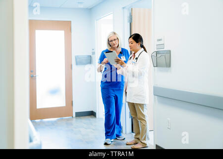 Weibliche Ärzte diskutieren über Tablet-PC beim Stehen in Krankenhaus Flur Stockfoto