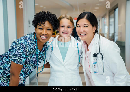 Portrait von fröhlichen Ärztinnen mit Mädchen tragen Laborkittel im Krankenhaus Stockfoto