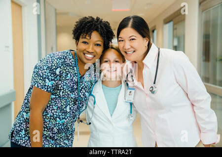 Portrait von zuversichtlich Ärztinnen mit Mädchen tragen Laborkittel im Krankenhaus Flur Stockfoto