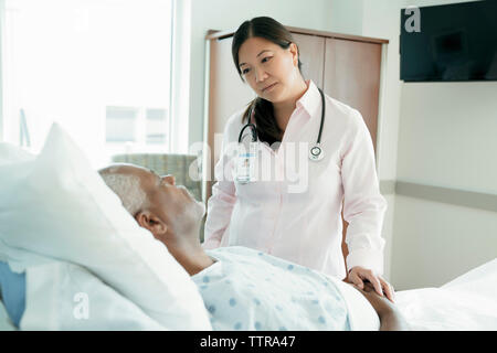 Ärztin mit Blick auf ältere Patienten liegend auf Bett im Krankenhaus Stockfoto