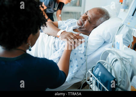 Vater berühren Hand's Tochter, während die weiblichen Arzt im Hintergrund arbeiten Stockfoto