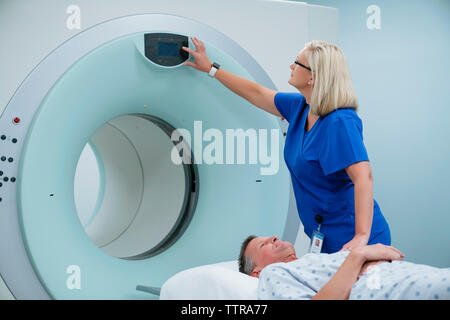 Krankenschwester einstellen Taste auf MRT-Scanner, während der Patient liegend im Untersuchungsraum Stockfoto