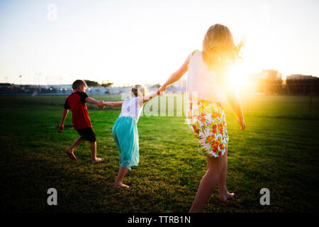 Mutter und Kinder spielen im Park bei Sonnenuntergang Stockfoto