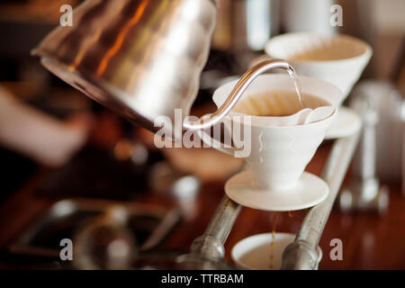 Wasser aus dem Wasserkocher in Kaffee Filter im Cafe gegossen Stockfoto