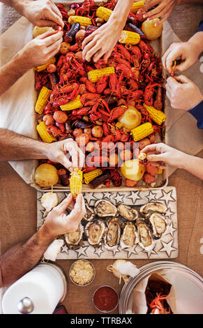 Ansicht von oben von Menschen essen eine crayfish Kochen mit Kartoffeln, Hühneraugen und Austern am Esstisch Stockfoto