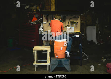 Ansicht der Rückseite des Jungen den Umgang mit Werkzeugen im Lager Stockfoto