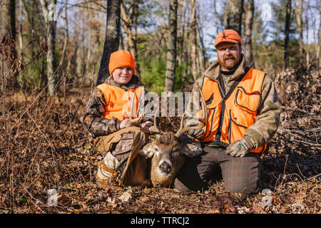 Portrait von Vater und Tochter mit toten Hirsch auf Feld während der Jagd Stockfoto