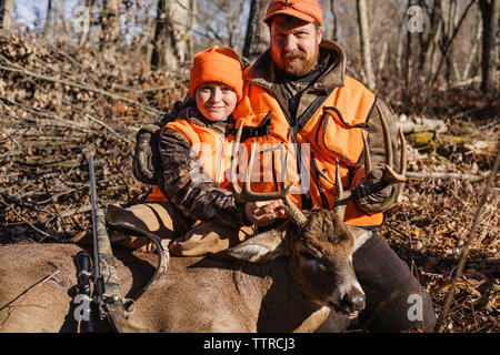 Portrait von Vater und Tochter mit toten Hirsch auf Feld Stockfoto