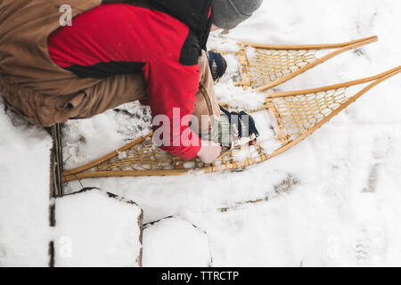 Hohe Betrachtungswinkel der Teenager tragen Schneeschuhe während der Sitzung auf schneebedeckten Feld Stockfoto