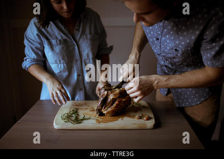 Paar schneiden gekochtes Lamm am Tisch Stockfoto