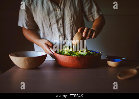 Mittelteil der Frau Einfüllen von Öl in die Avocado und Spinat Salat zu Hause Stockfoto