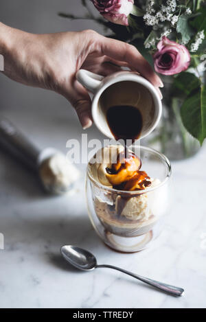 7/8 Bild der Frau gießen Schokolade Soße auf affogato Stockfoto