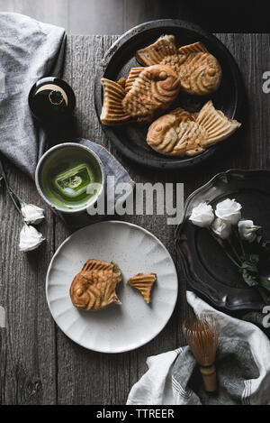 Ansicht von oben Der taiyaki mit Matcha Tee und Rosen auf hölzernen Tisch Stockfoto