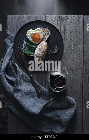 Draufsicht des Herzens Form sunny side up Ei mit geröstetem Brot am Tisch serviert Stockfoto
