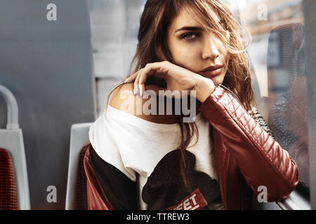 Portrait von selbstbewussten jungen Frau aus Leder Jacke sitzen im Bus Stockfoto