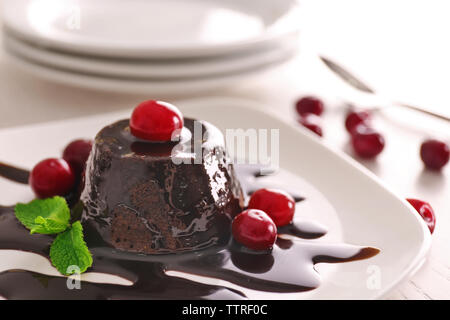 Leckere Schokolade Fondant Kuchen mit frischen Kirschen und Minze auf Platte Stockfoto