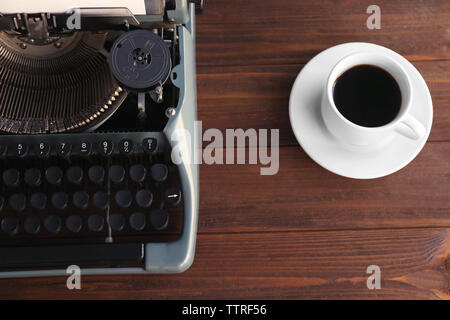 Alte Schreibmaschine und Tasse Kaffee auf dem Tisch, Ansicht von oben Stockfoto